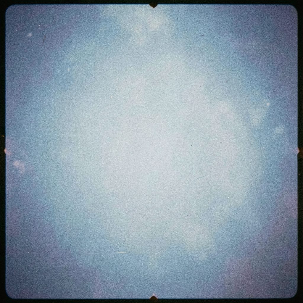 Close-up analog photograph of a circuit board lit in cool blue tones with visible film grain