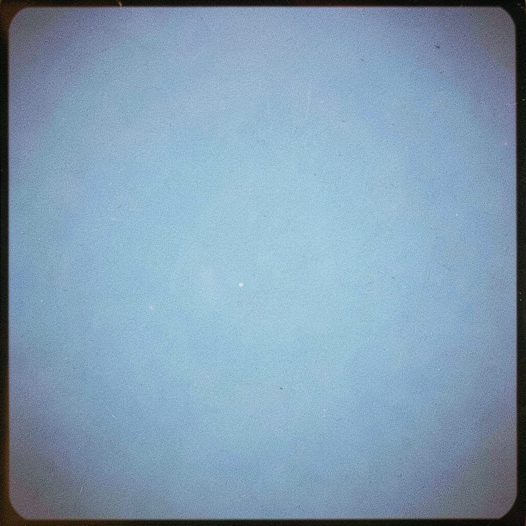 Moody analog photograph of a glowing blue world map overlaid with circuit board traces, soft grain texture, deep navy tones